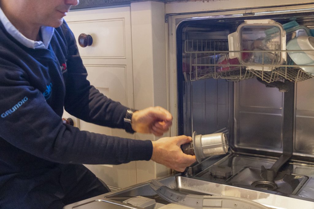 Technician performing dishwasher maintenance and replacement parts installation