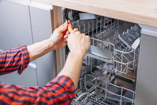 Technician performing dishwasher repair and maintenance in a residential kitchen in Pawleys Island, SC