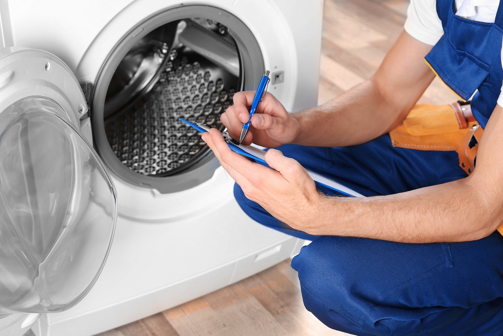 Technician diagnosing a front-load washing machine to prevent humidity-related issues.