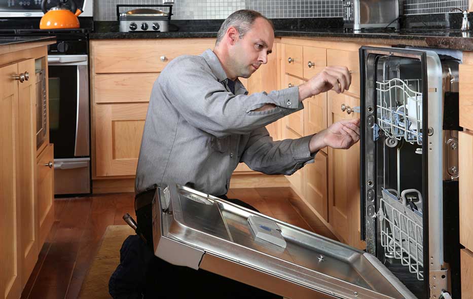 Appliance repair technician servicing a built-in dishwasher in North Myrtle Beach