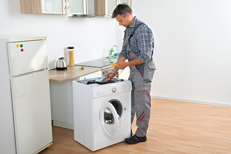 Appliance repair technician servicing a front-load washing machine in a residential kitchen in North Myrtle Beach, SC