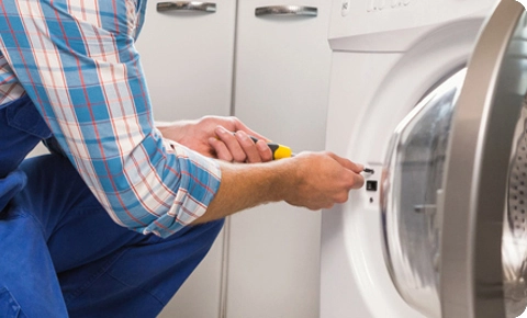 Appliance repair technician servicing a front-load washing machine.