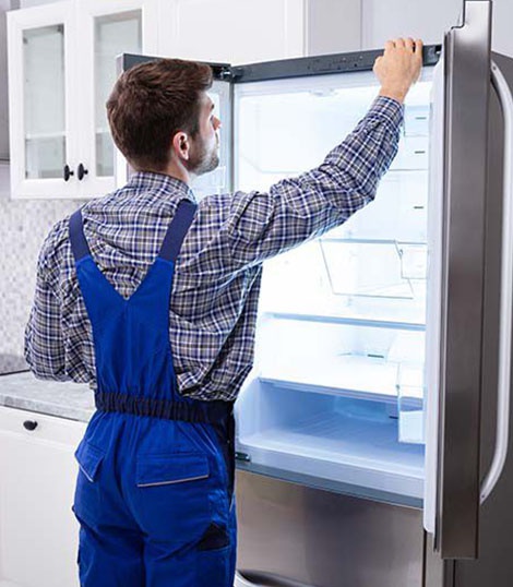 Technician checking refrigerator condenser coils and compressor system in Myrtle Beach SC
