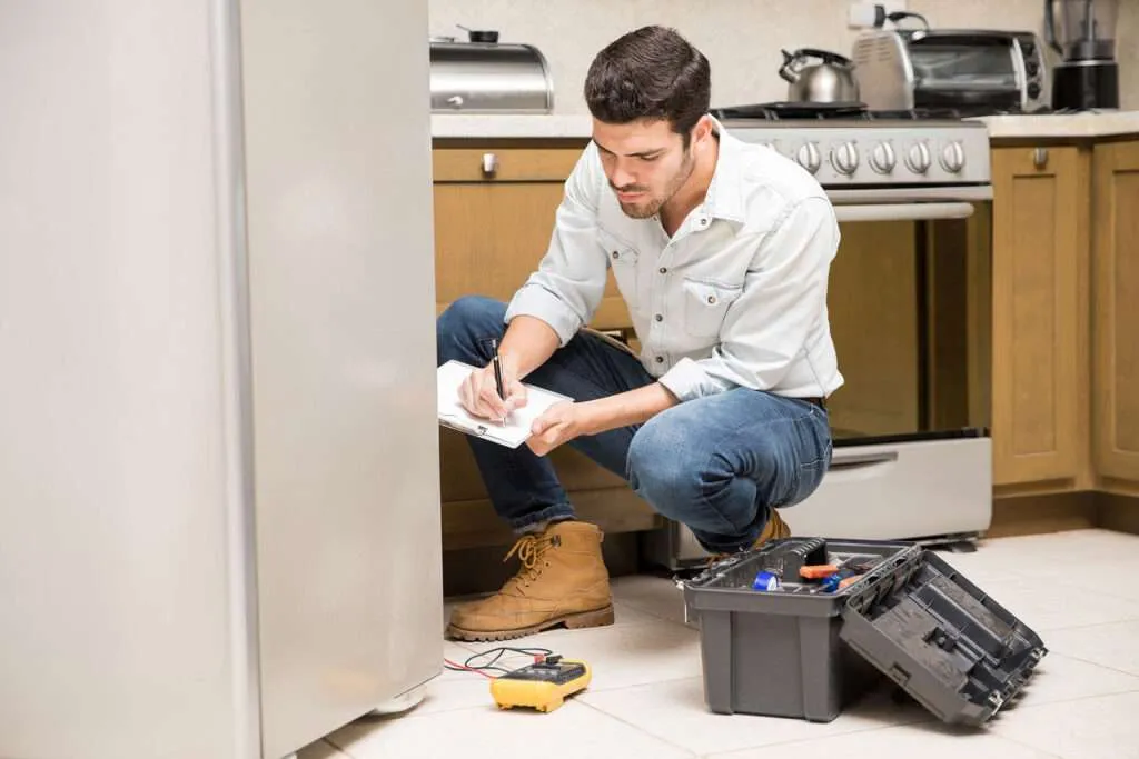 Technician diagnosing a residential refrigerator during an appliance repair service in Carolina Forest, SC