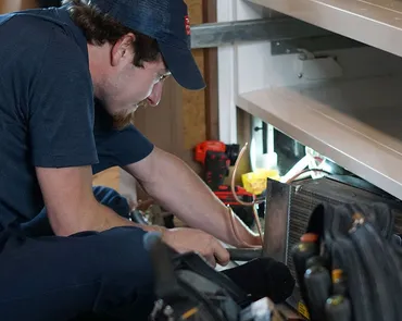 Technician diagnosing a residential refrigerator during an appliance repair service in Surfside Beach, SC
